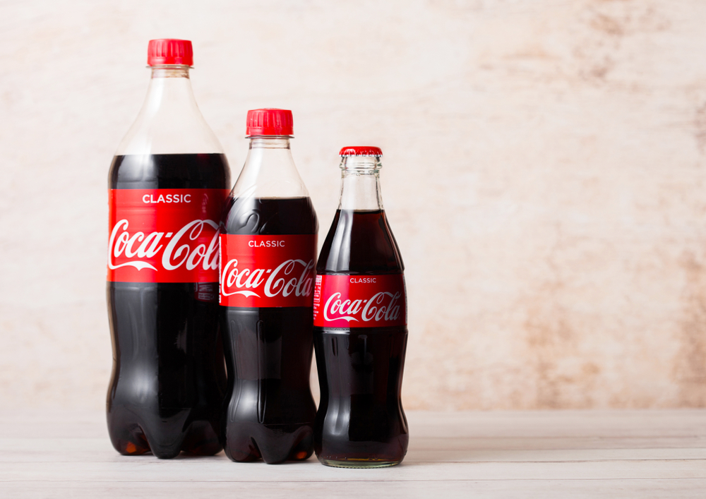 lastic and glass bottles of Original Coca-Cola soft drink on wood. Most popular drink in the world.