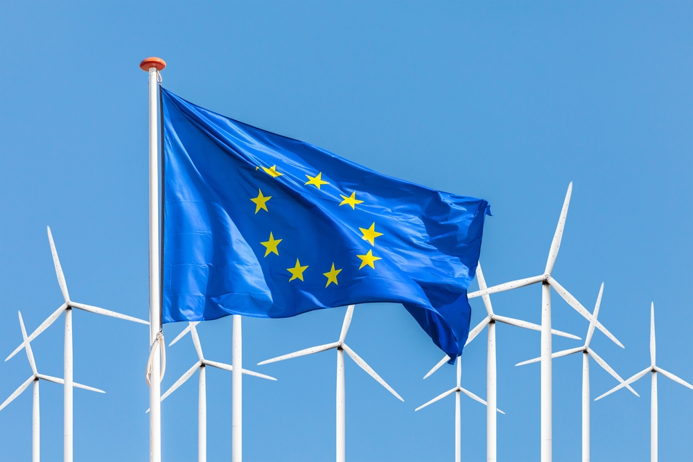 Official flag of the European Union in front of a large windpark with wind turbines The European Commission has unveiled the European Sustainability Reporting Standards (ESRS) which will affect more than 50,000 companies.