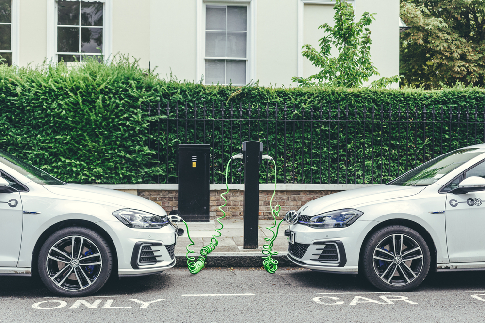 two white EV Volkswagen Golf GTE cars charging at a charging point on a street in London.