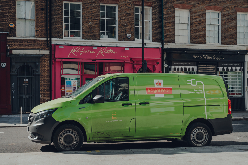 Green electric Royal Mail van on a street in London.