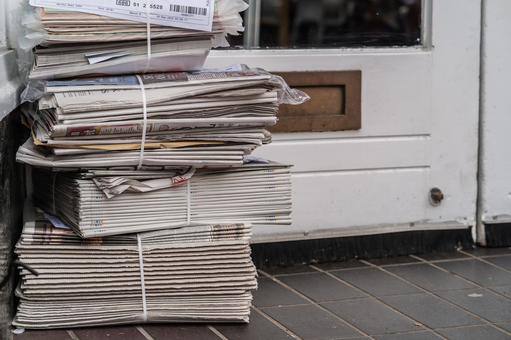 A pile of fresh newspapers with a white door in the background. newspaper printing