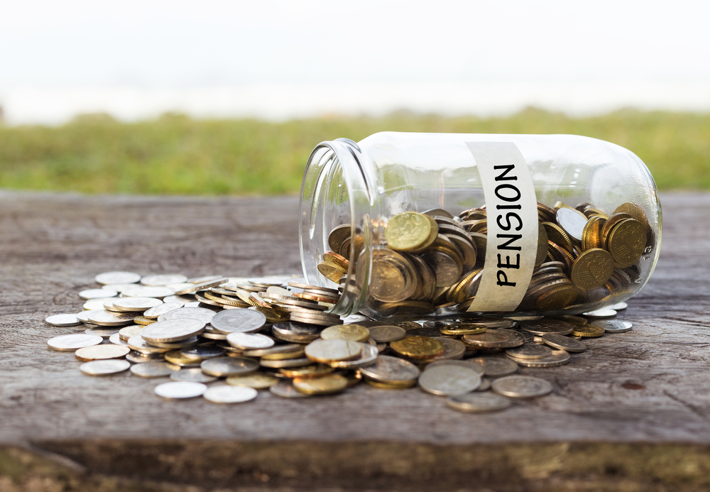 Coins in the jar or glass on the wood with PENSION label against bokeh beach background. Financial concept. Selective focus. ClientEarth has written to 12 largest pension funds warning that investing in fossil fuels could lead to legal risk.
